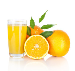Glass of fresh orange juice and orange fruits with green leaves