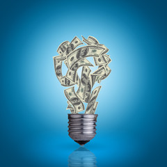 light bulb with money banknotes inside it on blue background
