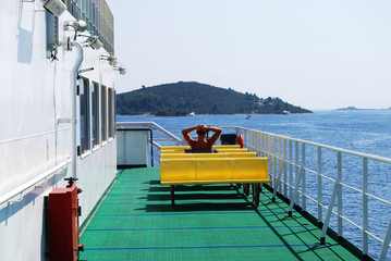 Mediterranean ferry deck yellow benches sitting man