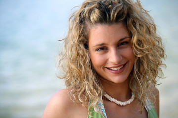 Cute curly-haired blond stood by the ocean