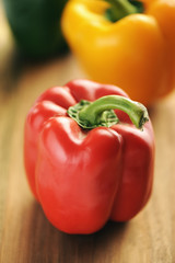 Red, yellow and green bell peppers on a wooden background.