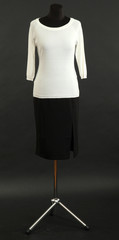 White blouse and black skirt on mannequin on black background