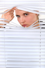 young woman looking through the blinds