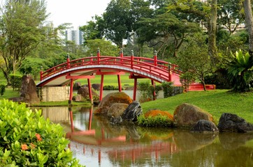 Curved red bridge over stream in Japanese Gardens, Singapore.