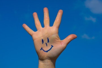 Human palm with smile on blue sky background