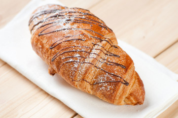 Crispy croissant with chocolate icing on wooden boards