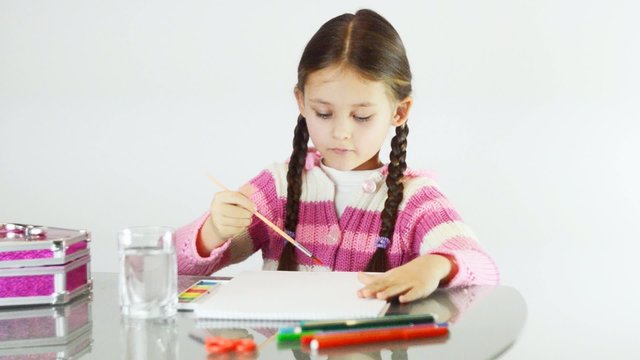 little girl draws a heart in the album watercolors
