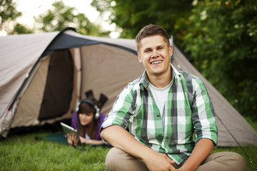 Young man sitting in front of tent