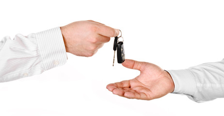Male hand holding a car key and handing it over to another perso