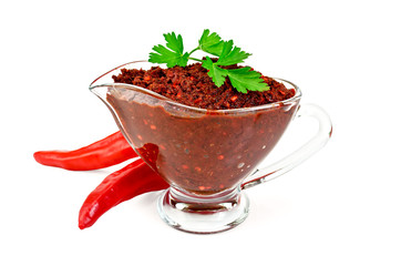 Ajika in a glass gravy boat with two hot peppers