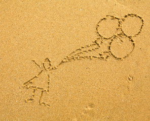 Fototapeta na wymiar Rysowanie na piasku: dziecko z balonami.