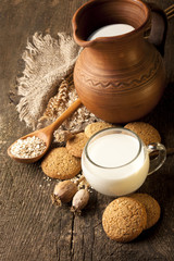 oatmeal cookies and jug of milk on old wooden table