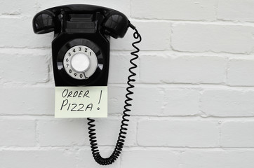 Black retro telephone with reminder note to order pizza