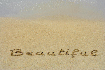 Conceptual handwritten text beautifue in sand