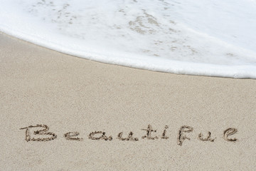 Conceptual handwritten text beautifue in sand
