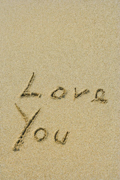 Conceptual handwritten love you text in sand