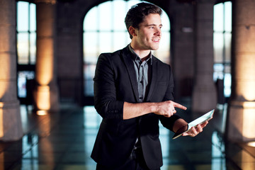 Homme souriant pointant une tablette