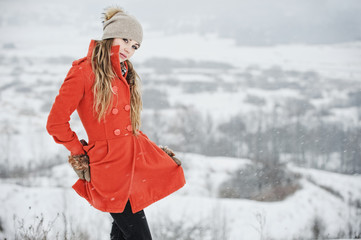Fototapeta Młoda dziewczyna w pomaranczowym płaszczu na śniegu obraz