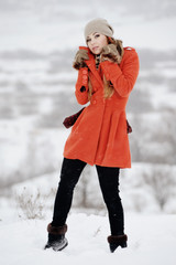 Młoda dziewczyna w pomaranczowym płaszczu na śniegu