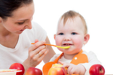 young mother spoon-feeding her baby girl