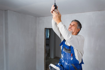 Senior man installing a bulb in a freshly renovated appartment
