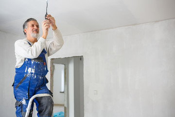 Senior man installing a bulb in a freshly renovated appartment