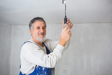 Senior man installing a bulb in a freshly renovated appartment