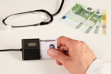Arzt steckt Gesundheitskarte in Kartenleser