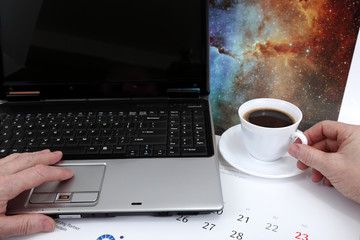Laptop, dłonie i kawa na biurku.