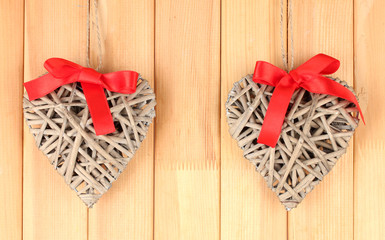 Wicker hearts with red bow on wooden background