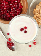Glass of yoghurt dessert with berries, on tablecloth background