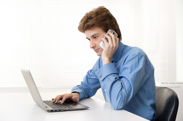 Man talking on phone in front of the laptop