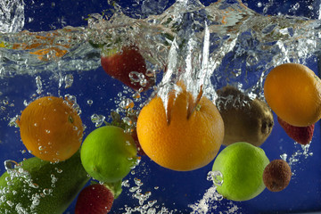Les fruits éclaboussent dans l& 39 eau avec des bulles sur fond bleu