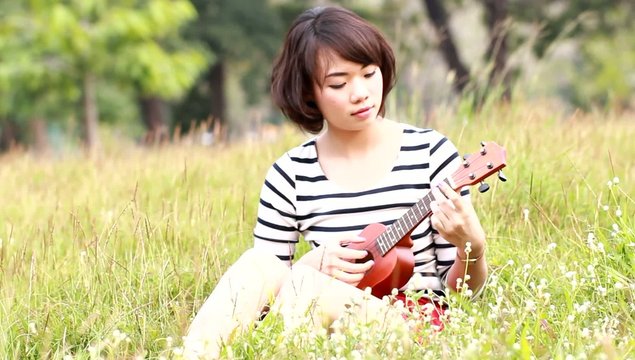 Thai woman with Ukulele in meadow