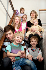 Big happy family sitting on the stairs at home.