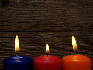 Fototapeta na wymiar Three burning candles on wooden background