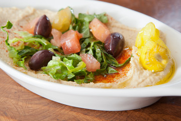 Bowl of hummus garnished with salad and pepper