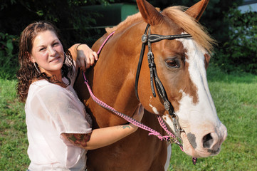 Young adult woman holding her horse