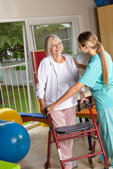Physiotherapeutin erklärt Seniorin einen Rollator