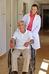 Altenpflegerin mit Senior im Rollstuhl