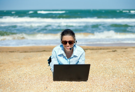 Business woman talking using her laptop on the beach