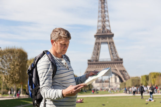  man - traveler near  Eiffel Tower looks in  map of  city