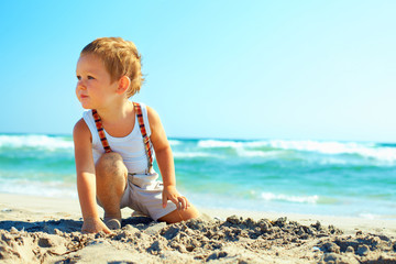 Fototapeta na wymiar thoughtful baby boy sitting on the beach