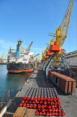 Pipe stack, ship ans train under crane bridge