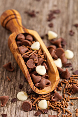Chocolate drops and sprinkles in a wooden scoop