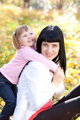 beautiful young mother and her daughter on the autumv forest