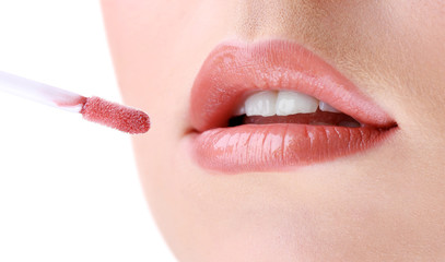 Beautiful young woman applying lip gloss, close up.