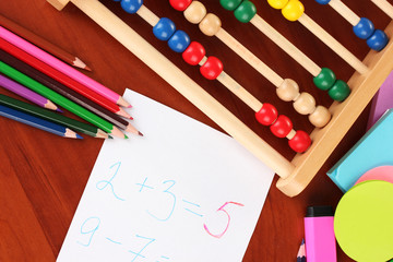 Toy abacus, note paper, pencils on bright background