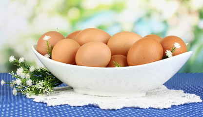 Eggs in white bowl on blue tablecloth close-up