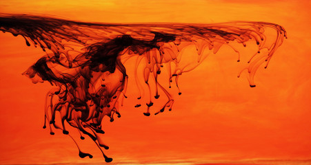 Black ink dispersing in orange water